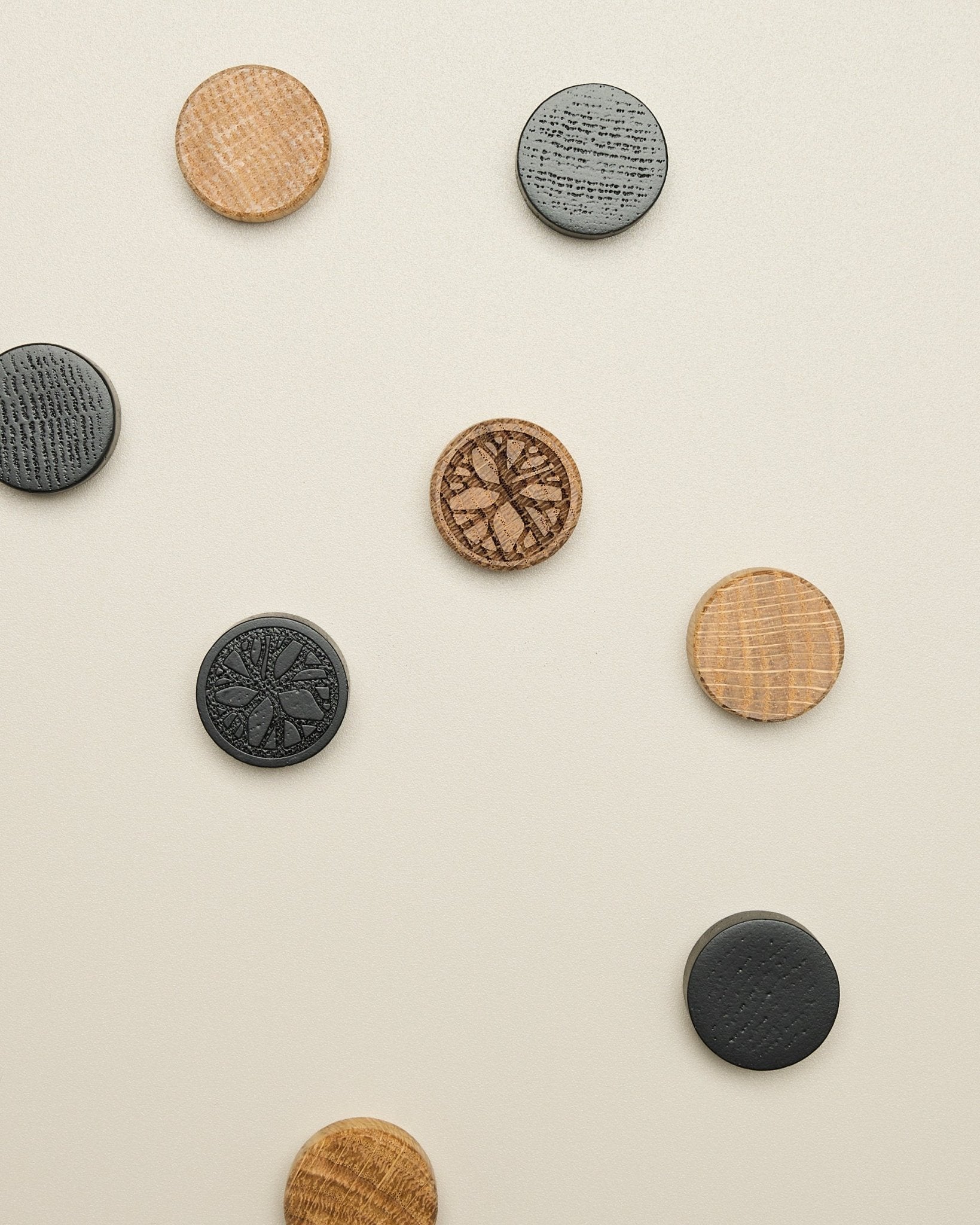 Norr Magnet set by WoodUpp includes four natural oak and black patterned disks, neatly positioned on a light beige surface; accessory for Akupanel.